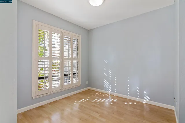 a view of an empty room with wooden floor and a bathroom