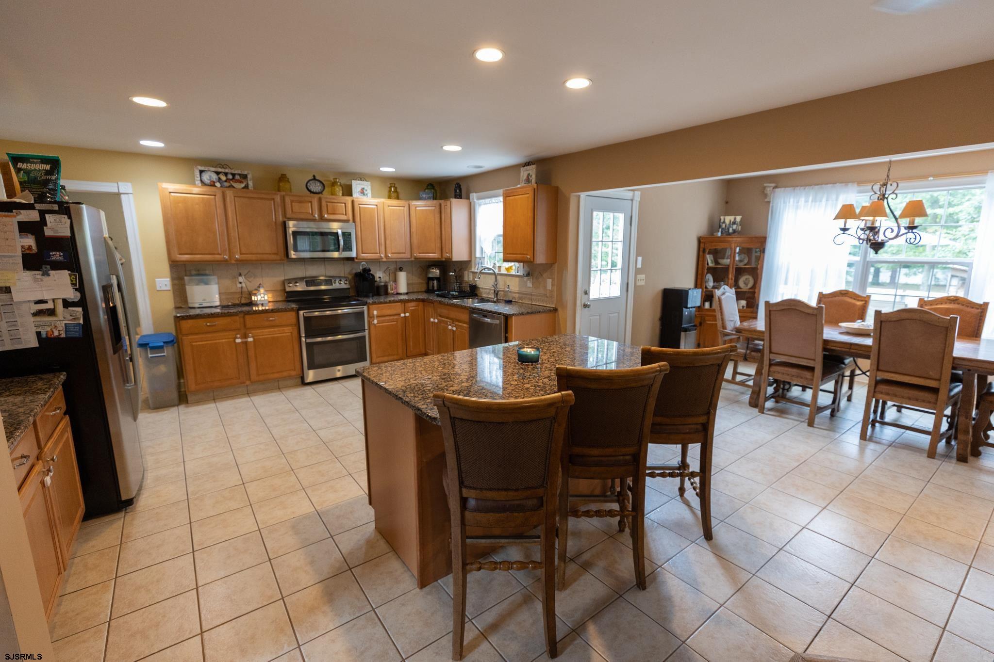 336 Old New York Road Port Republic, NJ 08241 - Photo 8 of 42 a kitchen with stainless steel appliances kitchen island granite countertop a table chairs and a refrigerator