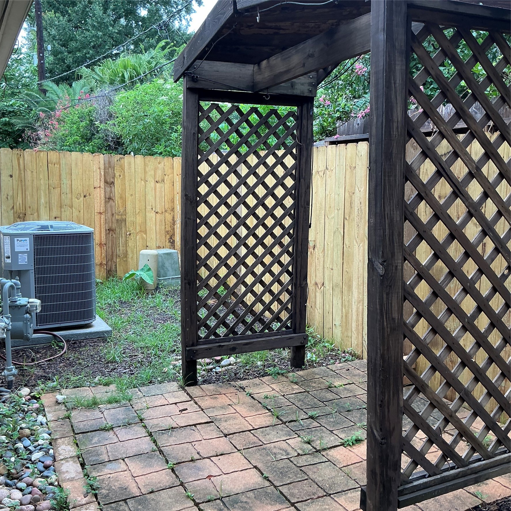 2910 Crescent Bend Road Spring, TX 77388 - Photo 25 of 29 Lovely backyard space with a brick patio, a wooden pergola with lattice panels, and a wooden privacy fence. There is also an air conditioning unit and some greenery, creating a cozy outdoor area.