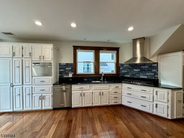 a kitchen with stainless steel appliances kitchen island granite countertop a stove a sink and white cabinets