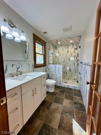 a spacious bathroom with a double vanity sink toilet mirror and shower