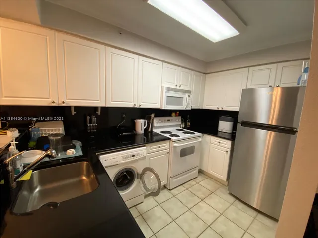 a kitchen with a refrigerator stove and white cabinets