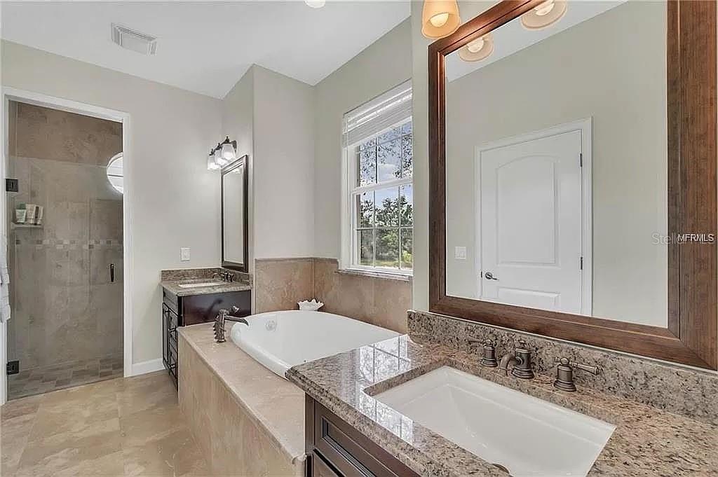 5526 Tiny Road Winter Garden, FL 34787 - Photo 16 of 39 a bathroom with a granite countertop sink a mirror and a shower