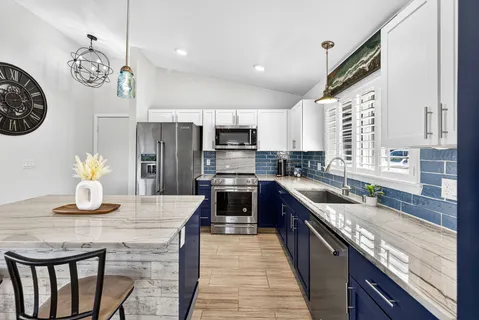 a kitchen with kitchen island granite countertop a sink dishwasher a stove a refrigerator a oven with a dining table and chairs