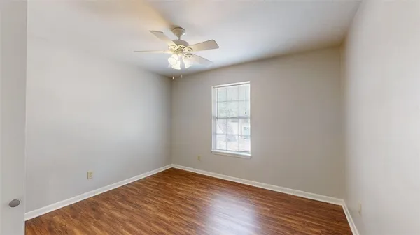 an empty room with wooden floor fan and windows