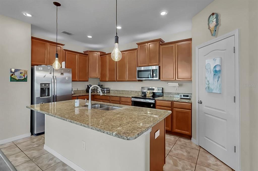 2408 Nighthawk Landing Court Ruskin, FL 33570 - Photo 16 of 50 a kitchen with stainless steel appliances granite countertop a sink a stove a refrigerator a center island a stove and cabinets