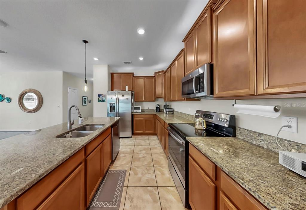 2408 Nighthawk Landing Court Ruskin, FL 33570 - Photo 18 of 50 a large kitchen with stainless steel appliances granite countertop a sink a stove and a wooden cabinets