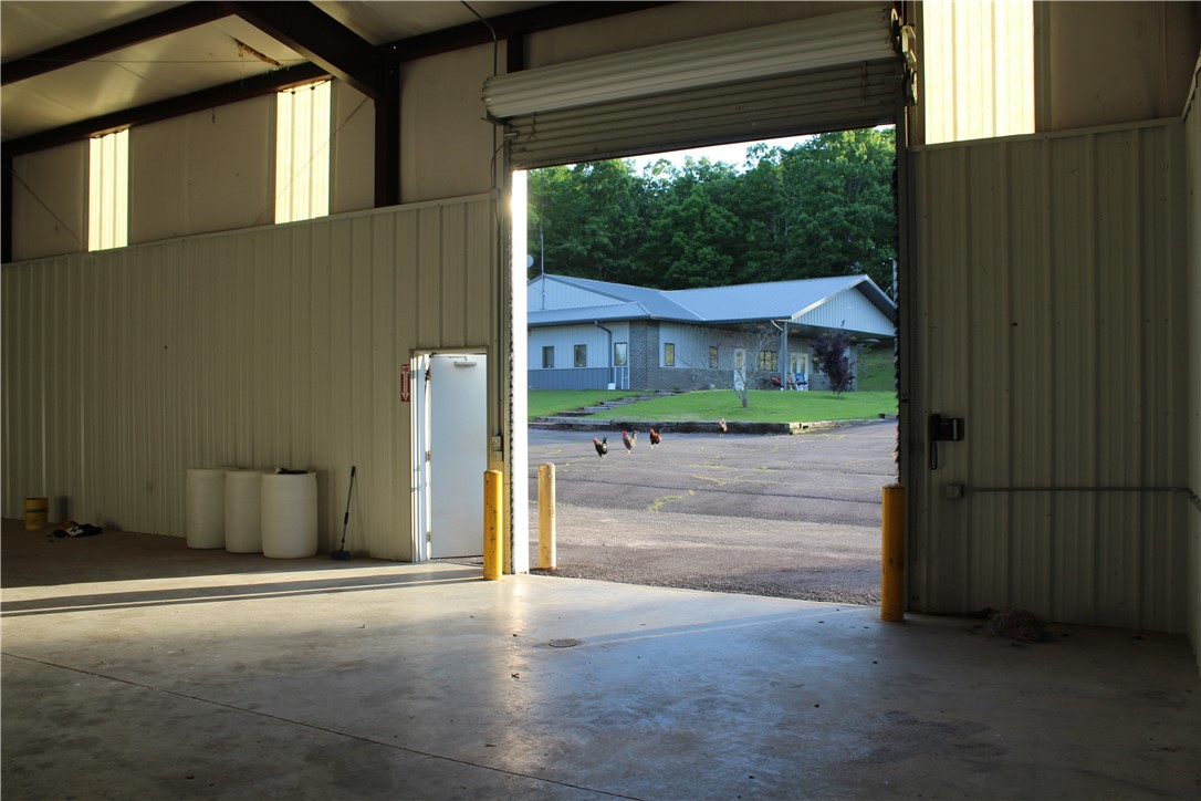 158 Ragon Road Tilly, AR 72679 - Photo 24 of 51 Spacious commercial interior featuring a concrete floor, corrugated metal walls, and a large roll-up door