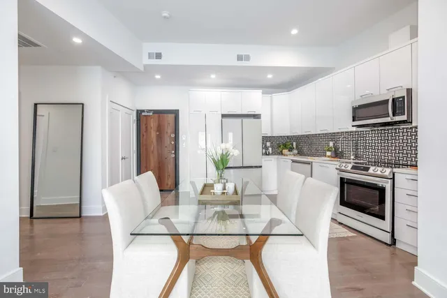 a kitchen with stainless steel appliances kitchen island granite countertop a refrigerator a stove a sink a dining table and chairs