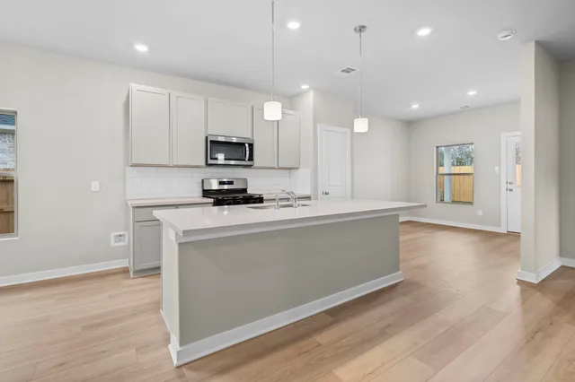 a kitchen with kitchen island a sink and a stove top oven