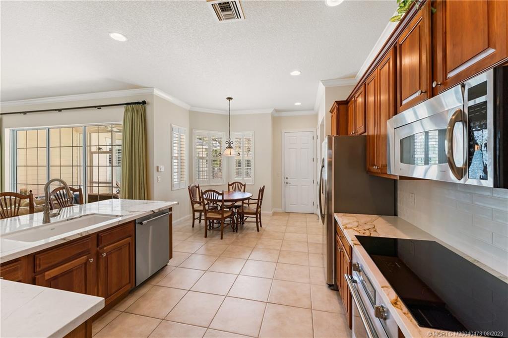 1162 Tropical Drive Jupiter, FL 33458 - Photo 15 of 43 a large kitchen with stainless steel appliances a sink and cabinets