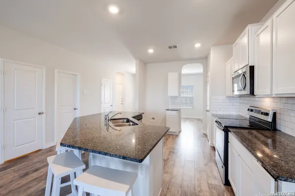 a kitchen with granite countertop kitchen island stainless steel appliances a sink a stove a table and chairs