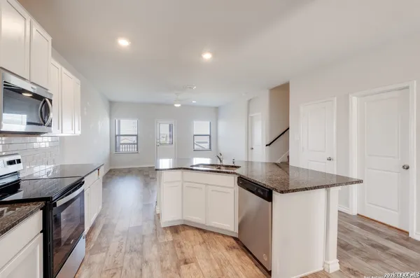a kitchen with granite countertop a sink a counter top space stainless steel appliances and cabinets