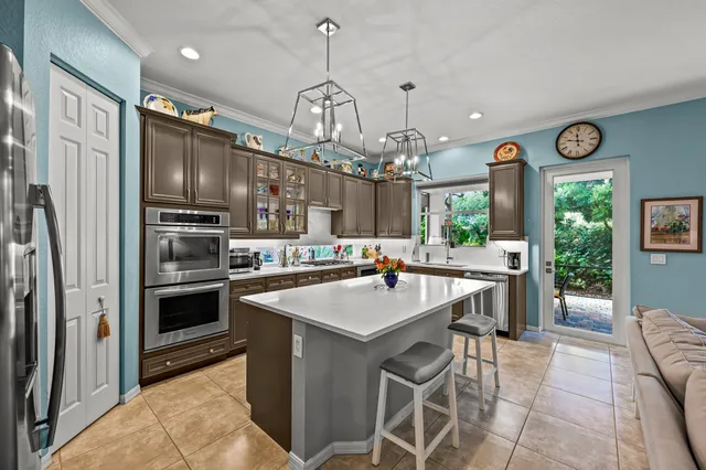 a kitchen with stainless steel appliances granite countertop a stove top oven a refrigerator and a chandelier