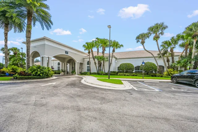 a view of a house with a yard and palm trees