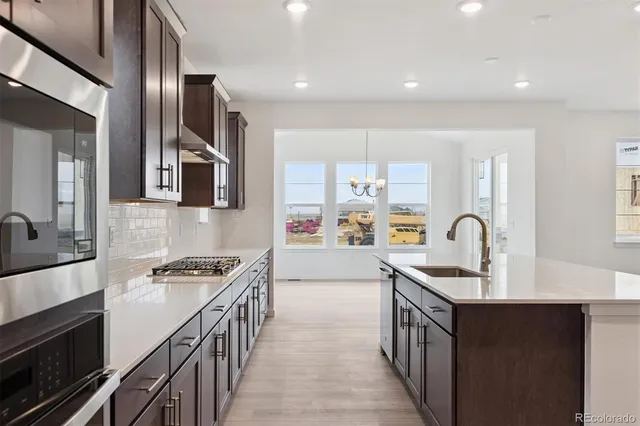 a kitchen with kitchen island stainless steel appliances a sink stove top oven and cabinets