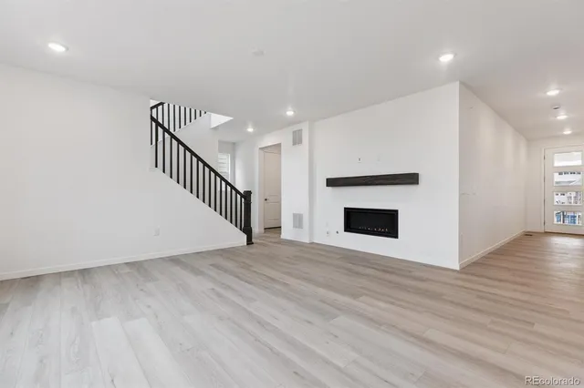 a view of an empty room with wooden floor and a fireplace
