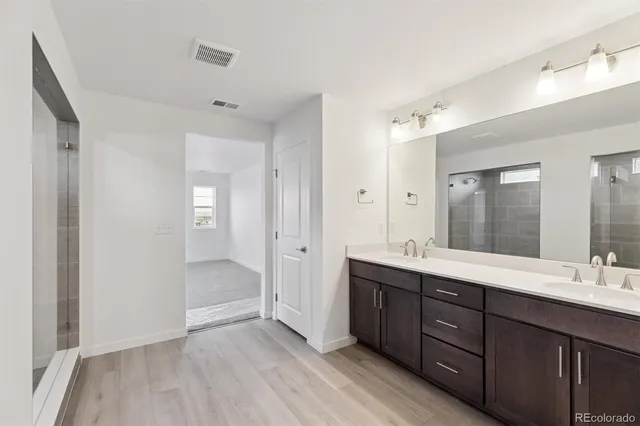 a bathroom with a double vanity sink and mirror with shower