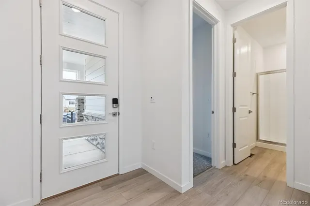 an empty room with wooden floor mirror and windows