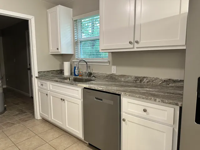 a kitchen with granite countertop white cabinets and a sink