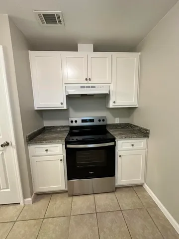 a kitchen with granite countertop white cabinets and appliances