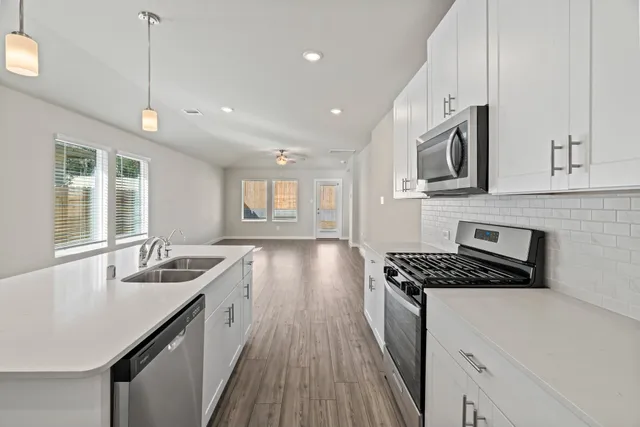 a kitchen with granite countertop a sink a counter space appliances and cabinets