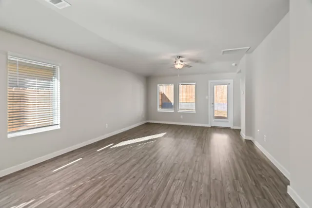 a view of an empty room with wooden floor and window