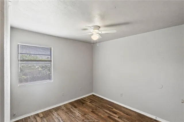 an empty room with a window and a fan