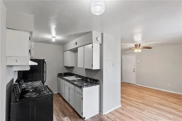 a kitchen with stainless steel appliances granite countertop a stove a refrigerator and a granite counter tops with white cabinets