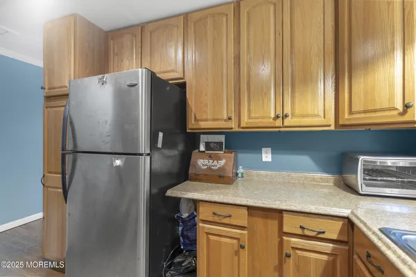 a kitchen with stainless steel appliances kitchen island granite countertop a table chairs and a refrigerator