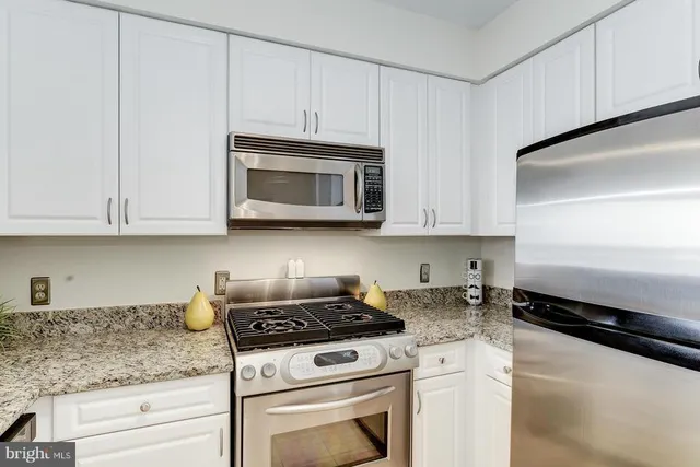 a kitchen with granite countertop white cabinets and stainless steel appliances