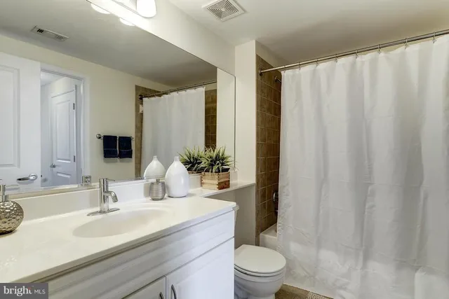 a bathroom with a granite countertop sink a toilet and shower