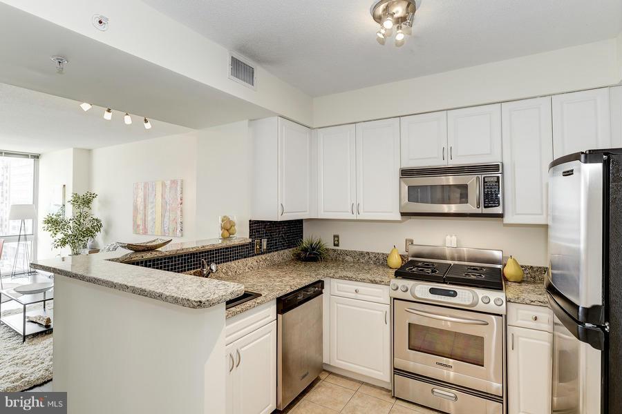 555 Massachusetts Avenue Northwest, Unit 806 Washington, DC 20001 - Photo 9 of 22 a kitchen with a sink a stove a microwave and refrigerator