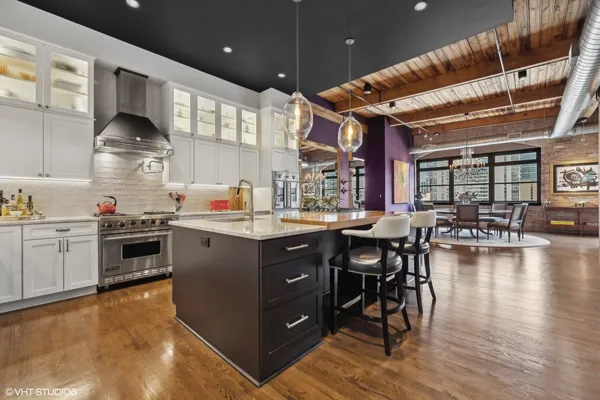 a kitchen with stainless steel appliances granite countertop a stove a sink dishwasher and a dining table with wooden cabinet
