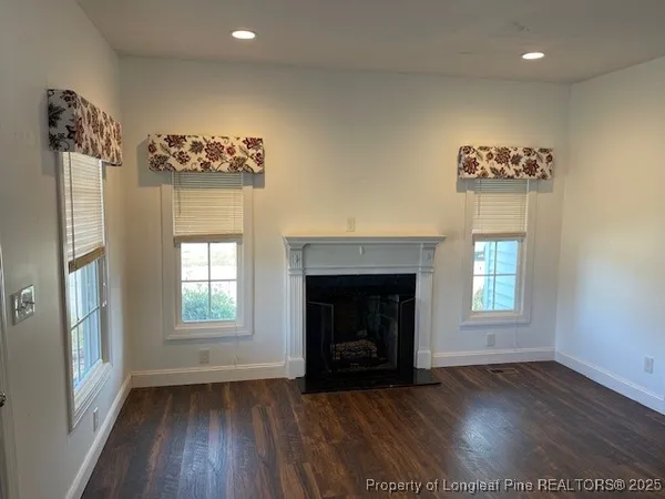 an empty room with windows and fireplace