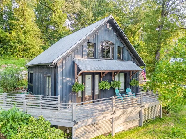 a view of a house with a yard plants and large tree