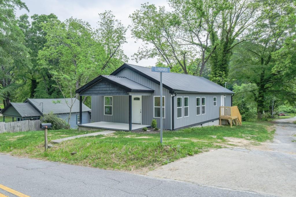 a view of a house with a yard and large trees