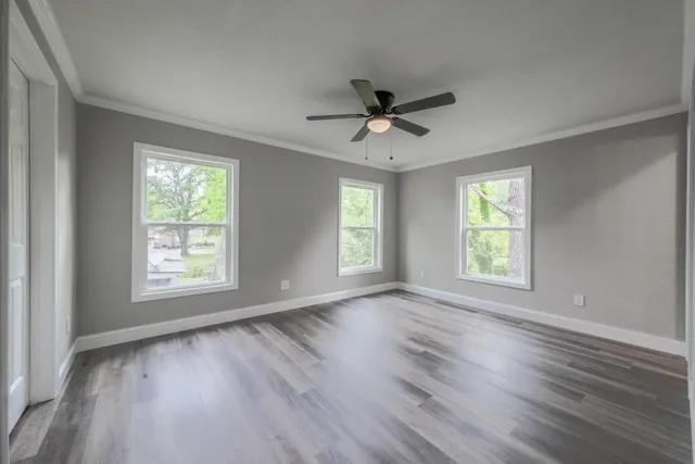a view of empty room with wooden floor and fan