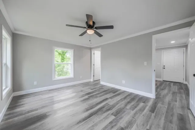a view of empty room with wooden floor and fan