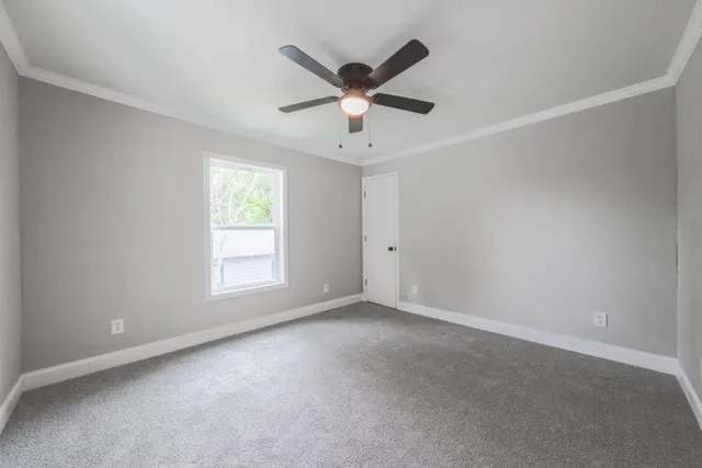 an empty room with ceiling fan and window