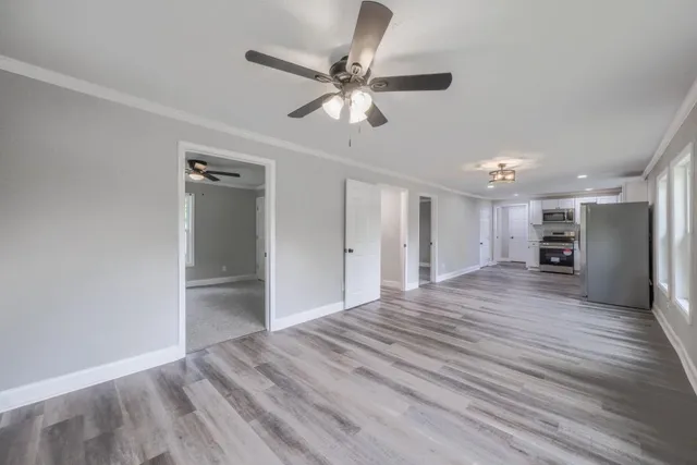a view of empty room with wooden floor and ceiling fan