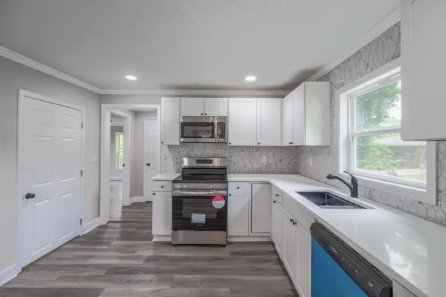 a kitchen with stainless steel appliances granite countertop a sink a stove a refrigerator cabinets and a window