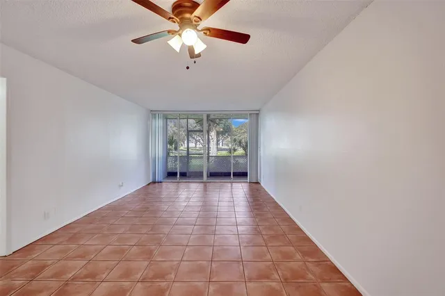 an empty room with chandelier fan and windows