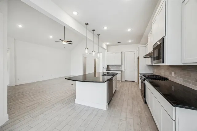 a kitchen with stainless steel appliances granite countertop a sink a stove and a wooden floors