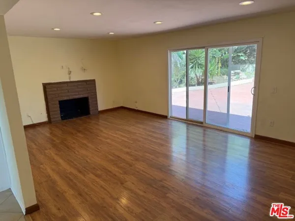 an empty room with wooden floor fireplace and windows