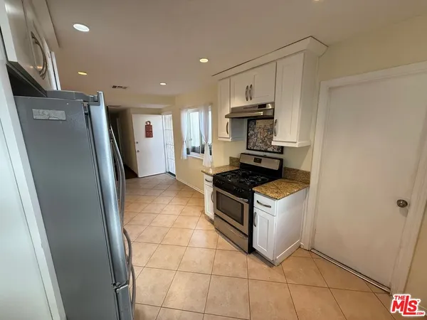 a kitchen with granite countertop a stove a refrigerator and a sink