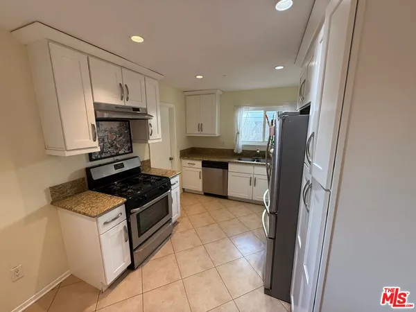a kitchen with granite countertop a refrigerator stove and sink