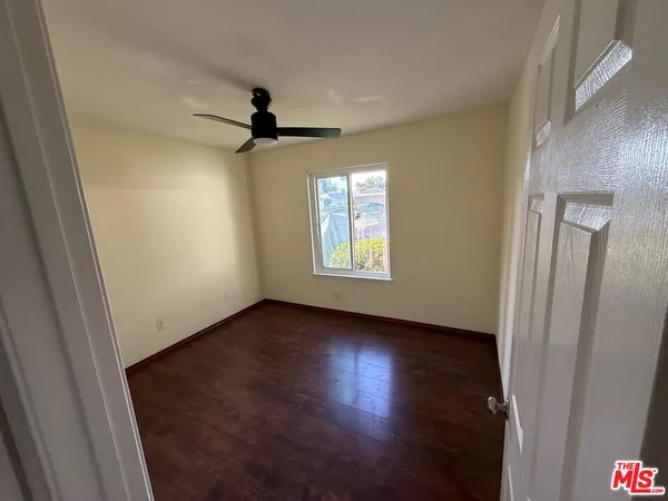 an empty room with wooden floor ceiling fan and windows