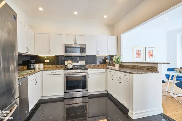 a kitchen with stainless steel appliances granite countertop a stove and white cabinets