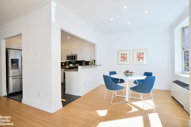 a dining room with wooden floor and kitchen view